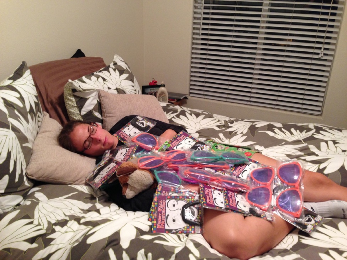 Kate asleep in bed covered in arcade prizes