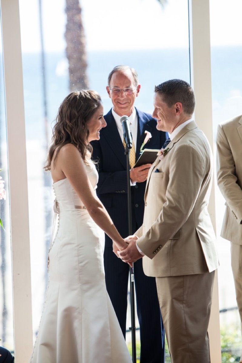 Kate and Kyle face to face holding hands during the ceremony with officiant behind them