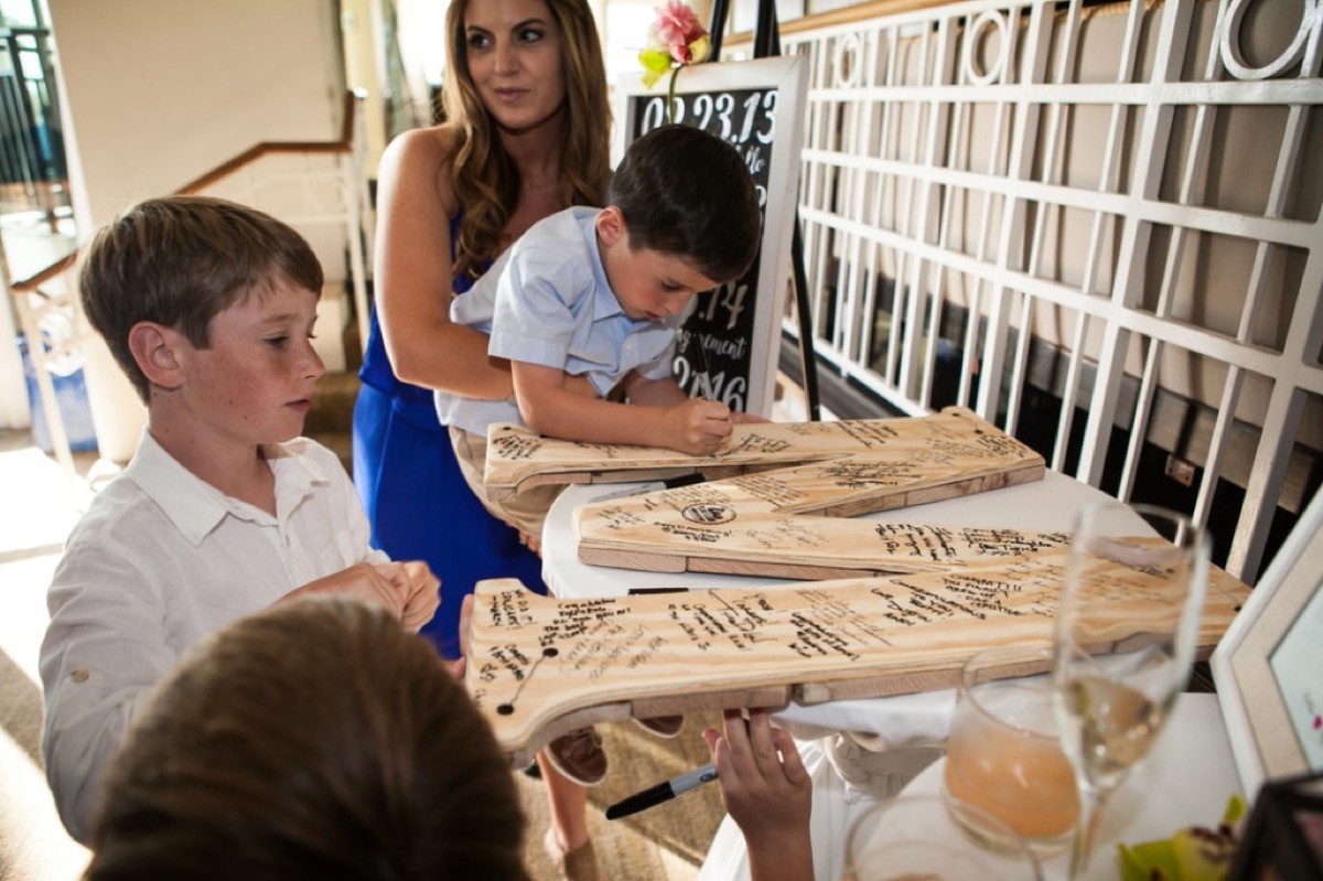 Children signing a large wooden letter M guestbook at the reception