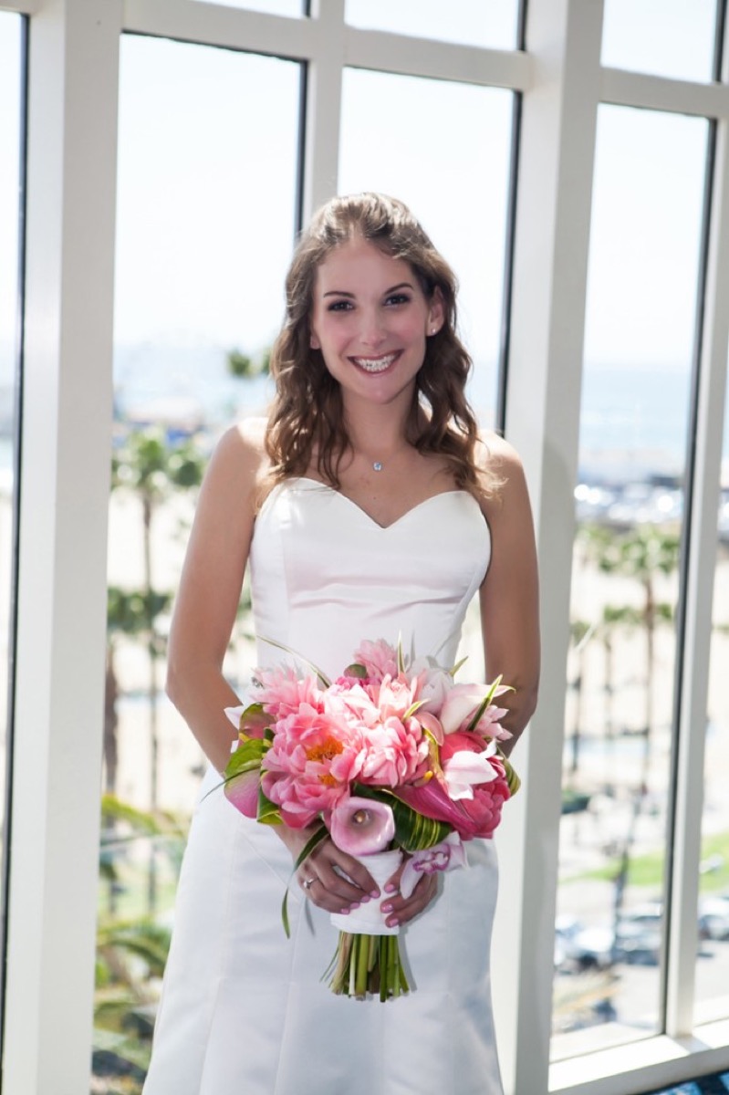 Kate in her wedding dress by the window overlooking the beach