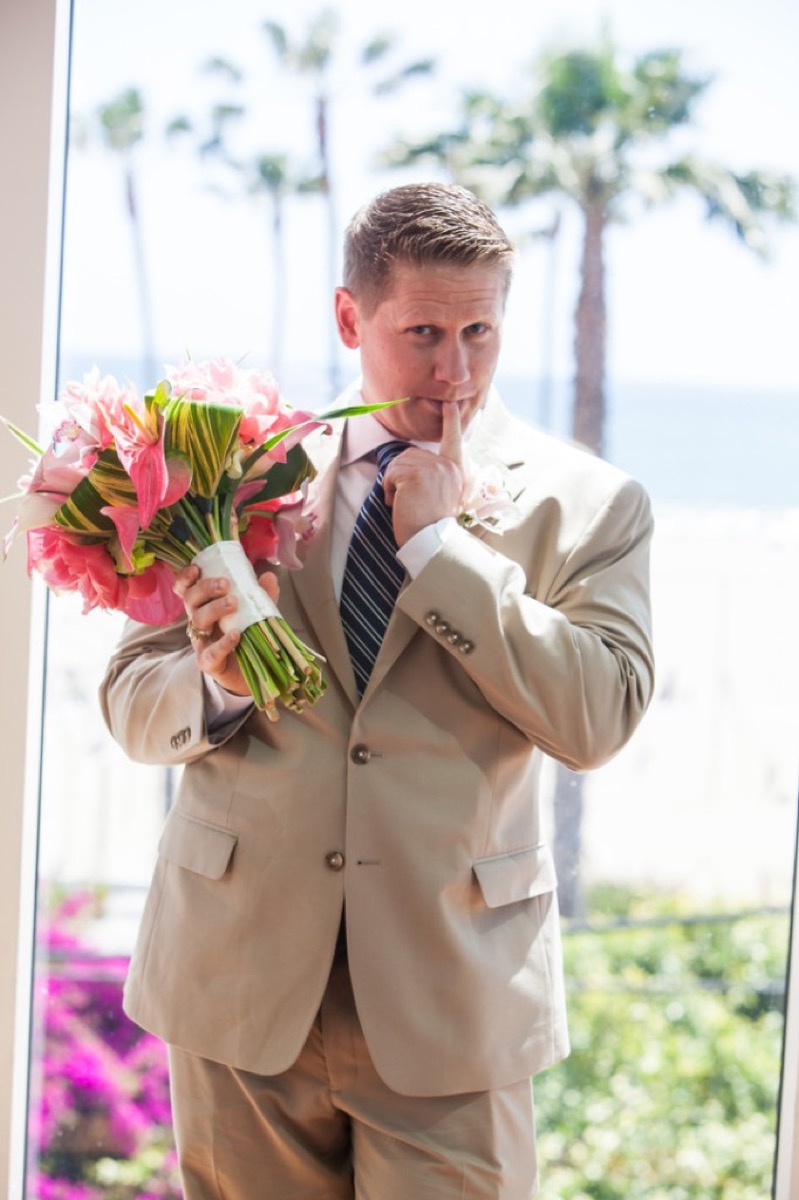 Kyle holding the bridal bouquet and shushing playfully