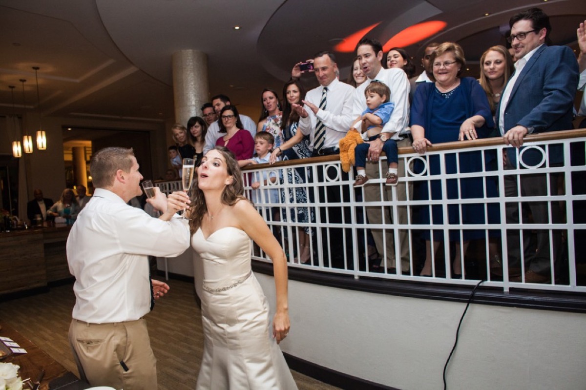 Wedding guests toasting Kyle and Kate from the balcony