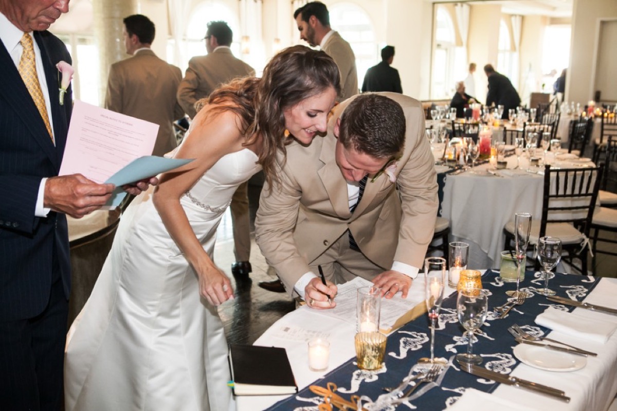Bride and groom signing the marriage license at a table with nautical seahorse runner