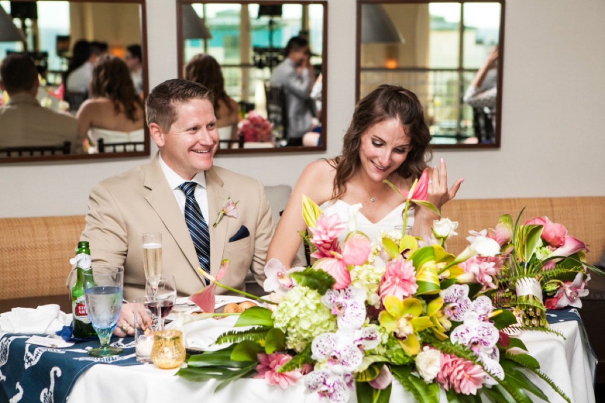 Kyle and Kate seated at the sweetheart table with tropical pink floral centerpiece