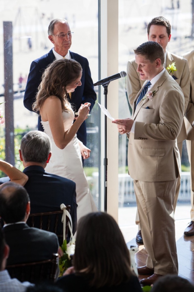 Kyle reading his vows into the microphone while Kate smiles