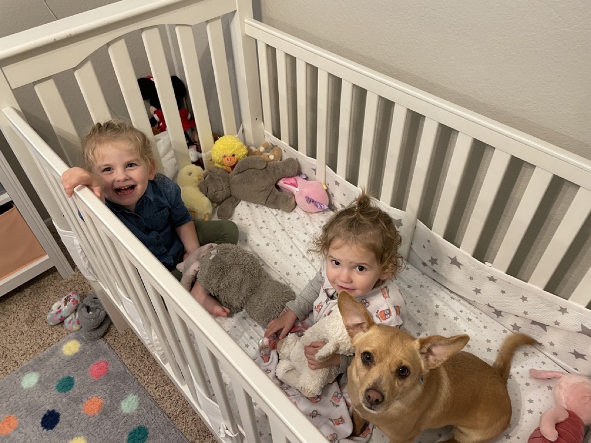 Makena, Morgan, and Buster the dog in the crib together