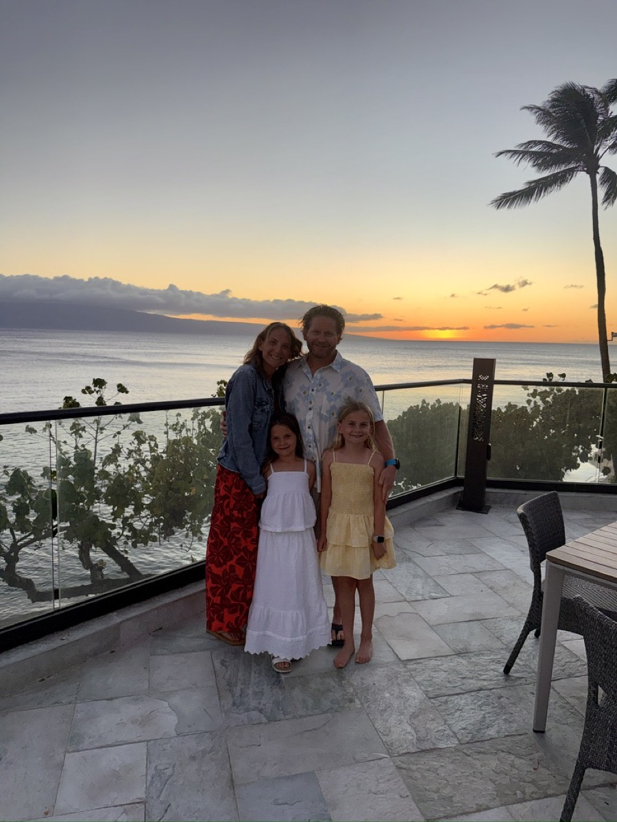 The family of four on a balcony overlooking the ocean at sunset in Maui